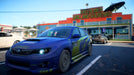 Blue Subaru rally car parked outside Green Men Grill and Souvenirs in Need for Speed Payback Deluxe Edition on Xbox" – This image features a blue Subaru rally car with custom decals, parked in front of a diner in Need for Speed Payback Deluxe Edition, available on Xbox. Perfect for players looking to enjoy high-speed street racing in an open-world environment