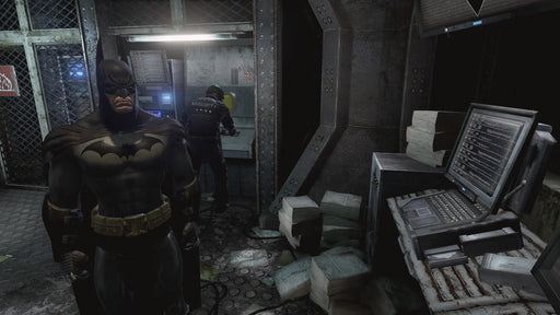 Batman stands in a dimly lit security room with a guard working on a console in Batman: Return to Arkham for Xbox One. Secure your Xbox One digital game key at RushGame.co and explore Arkham with enhanced visuals.