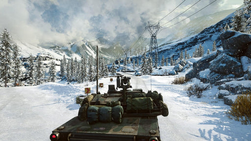 A military tank driving through a snowy mountain landscape in Battlefield 4, showcasing the game's stunning environmental details and dynamic weather effects. Get your game key now at RushGame.co.