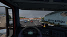 In-cabin view from Euro Truck Simulator 2 - Iberia DLC, showing a driver's perspective on a busy highway approaching a toll booth. The detailed dashboard and side mirrors enhance the realism. Get your Euro Truck Simulator 2 - Iberia DLC PC Steam CD Key now at RushGame.co for an immersive trucking adventure