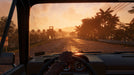 Gameplay screenshot - First-person driving perspective in Far Cry 6 PC, as the player navigates a tropical road at sunset, with palm trees and distant watchtowers lining the way. Buy your Ubisoft Connect CD Key US at RushGame.co and join the resistance against Antón Castillo