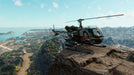 Gameplay screenshot - A military-style helicopter perched on a cliff in Far Cry 6 PC, offering a breathtaking view of Yara’s coastline and city skyline. Get your Ubisoft Connect CD Key US at RushGame.co and take to the skies in this explosive open-world adventure