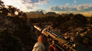 Far Cry 6 PC gameplay screenshot showing a player holding a golden custom rifle with a silencer, overlooking a stunning sunset-lit jungle landscape in Yara. Buy your Ubisoft Connect CD Key US now at RushGame.co and explore the vast open world